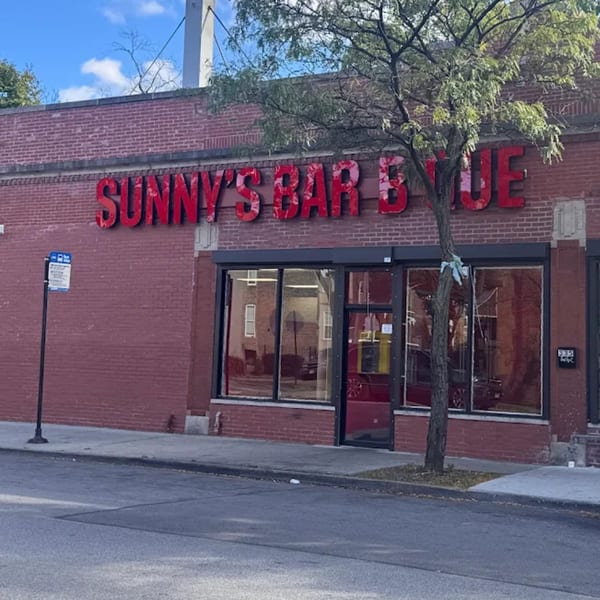 Exterior of Sunny's Bar B Que, a red brick building with large windows and red signage.