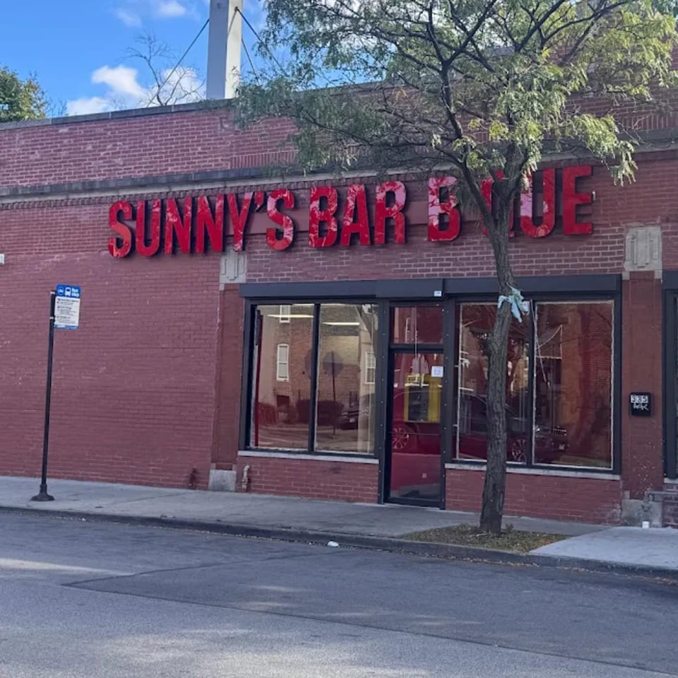 Exterior of Sunny's Bar B Que, a red brick building with large windows and red signage.
