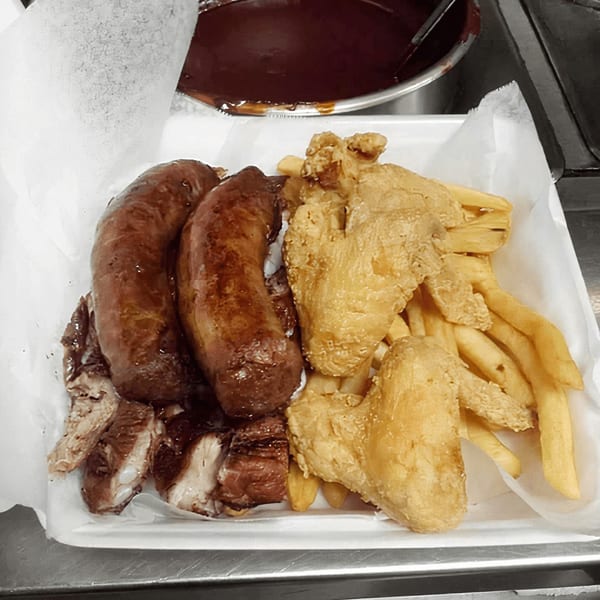 Sunny's Bar B Que platter with sausages, ribs, fried chicken wings, and french fries.